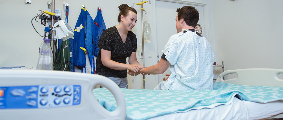 Graduate student with a patient sitting on a hospital bed