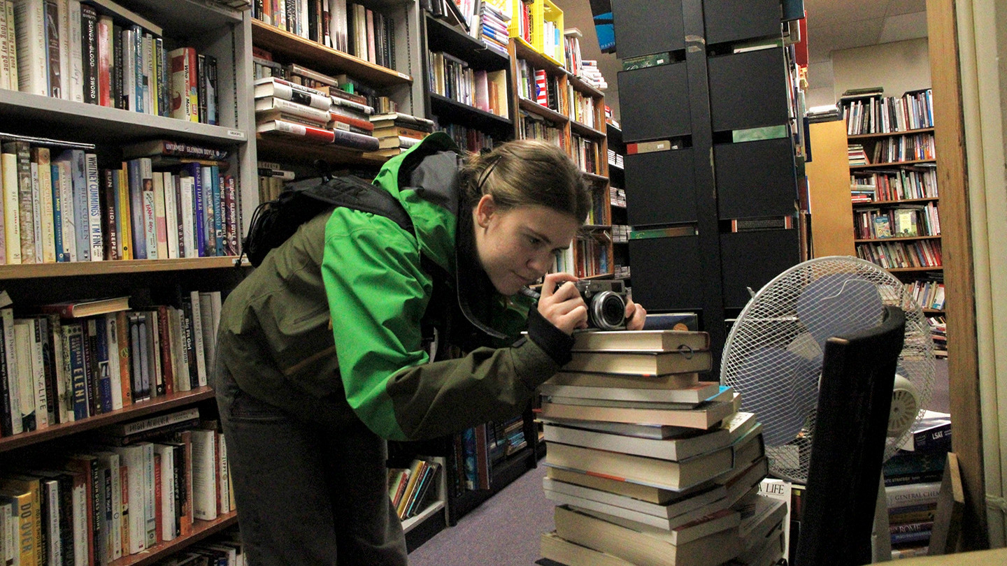 Aurora Campbell in a bookstore taking a photo with a camera.