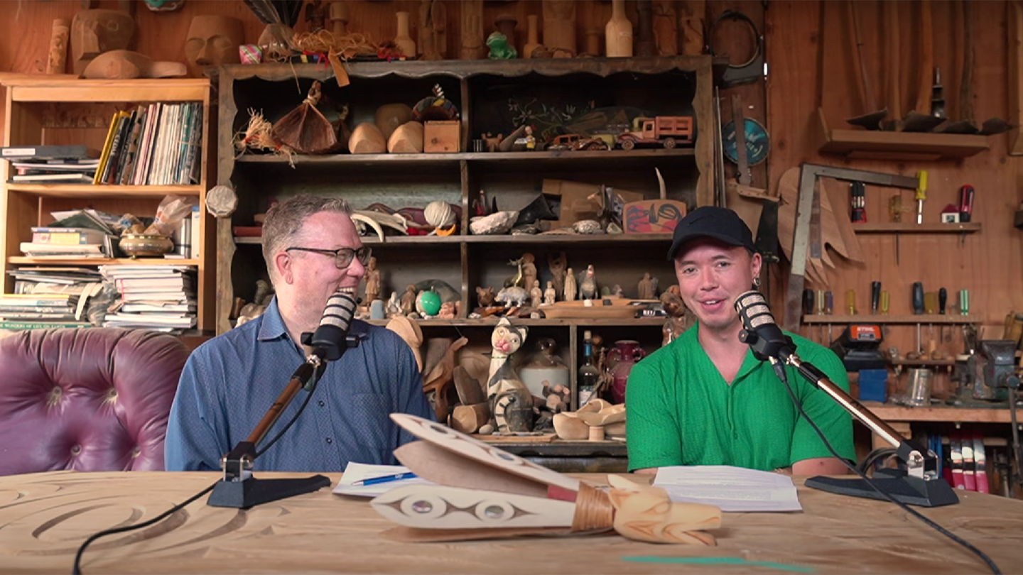 Jeff Ganohalidoh Corntassel (left) and Chazz Elliot (right) are recording a podcast with two microphones in a carving workshop.