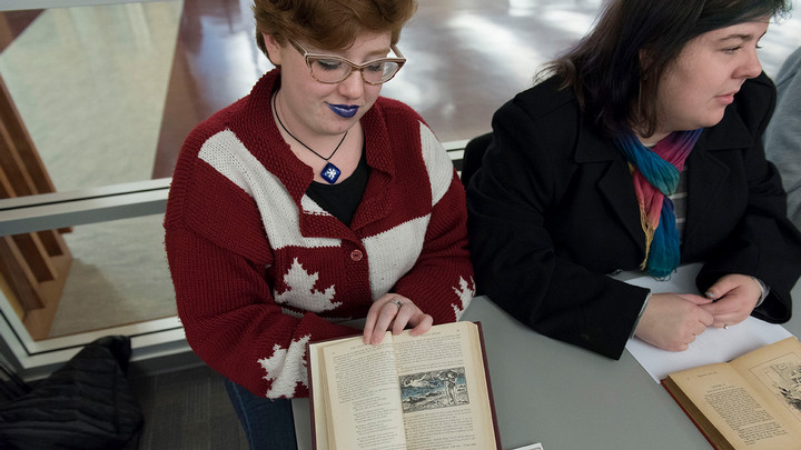 A student wearing sparkly eyeshadow and blue lipstick shows off a Victorian illustrated children's book.