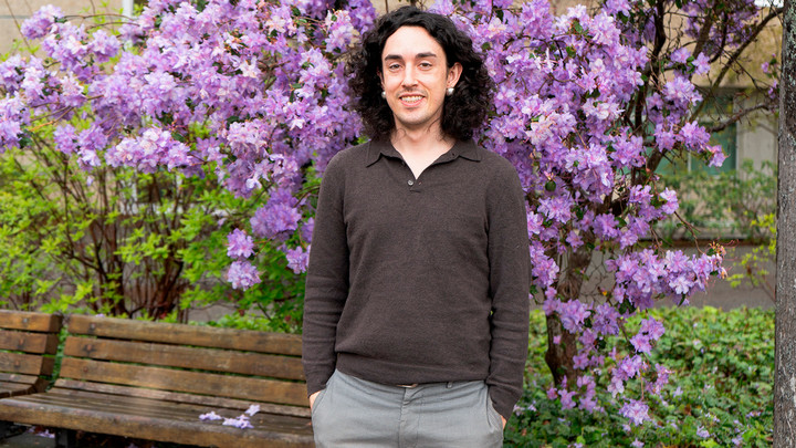 Eric Willis stands in front of a rhododentron in bloom.