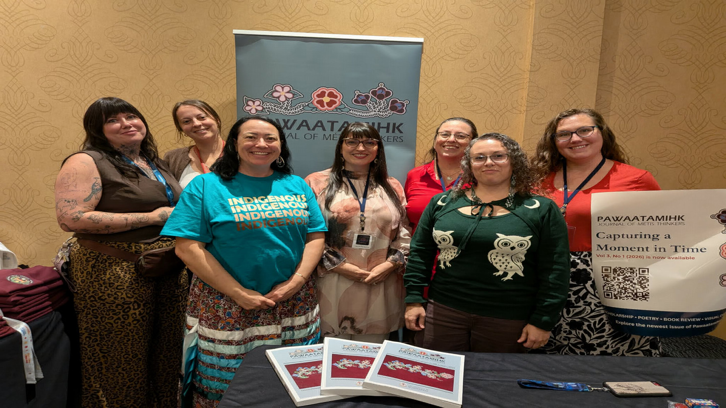 Several people pose in front of a pop-up banner at a conference.