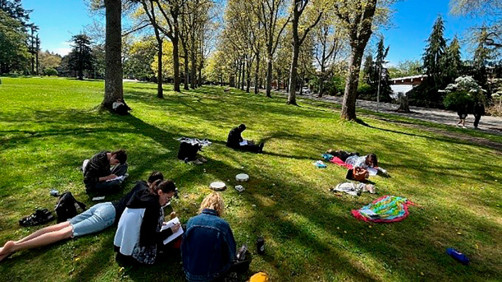 Students work individually on their writing on the grass in the UVic main quad.