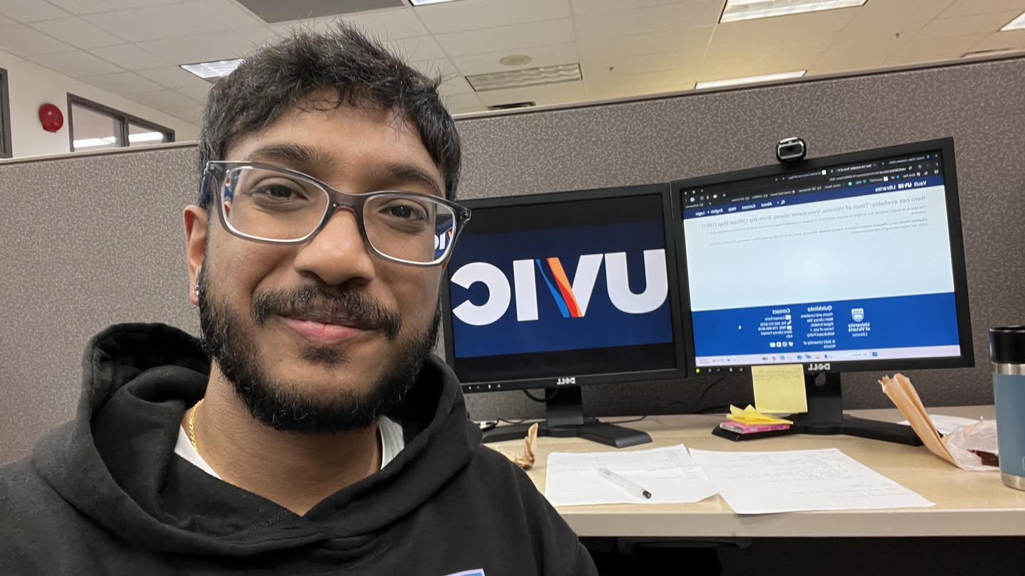 Sangeev at a desk in a cubicle.
