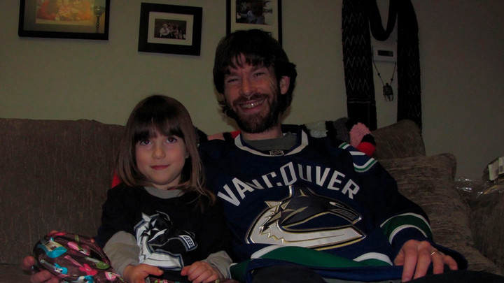 A young Sierra Vozel watches a hockey game with her dad, who wears a Canucks jersey.