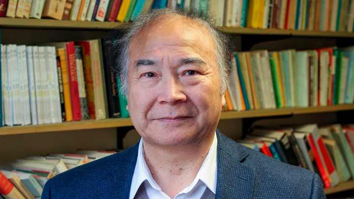Zhongping Chen in front of full bookshelves.