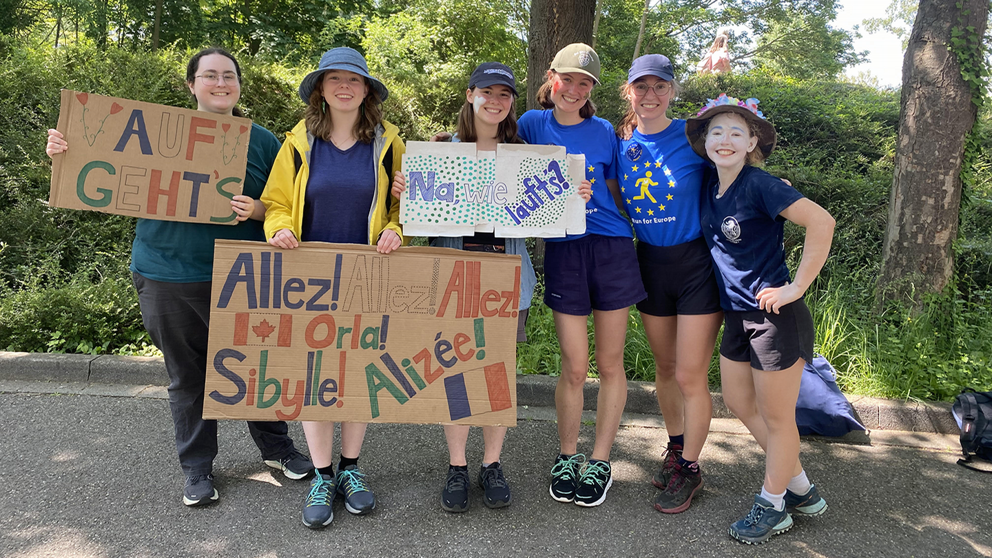 A group holds handmade signs in French and German.