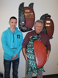 Temoseng Elliot Jr. and his father, world-renowned Coast Salish carver Temosen-THUT Charles Elliott, delivering a plaque they carved together for the Faculty of Humanities in 2002.
