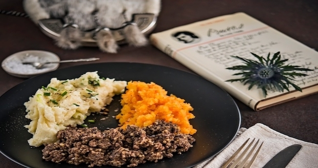 Photo of traditional meal, with thistle, book of poetry and sporran in the background.