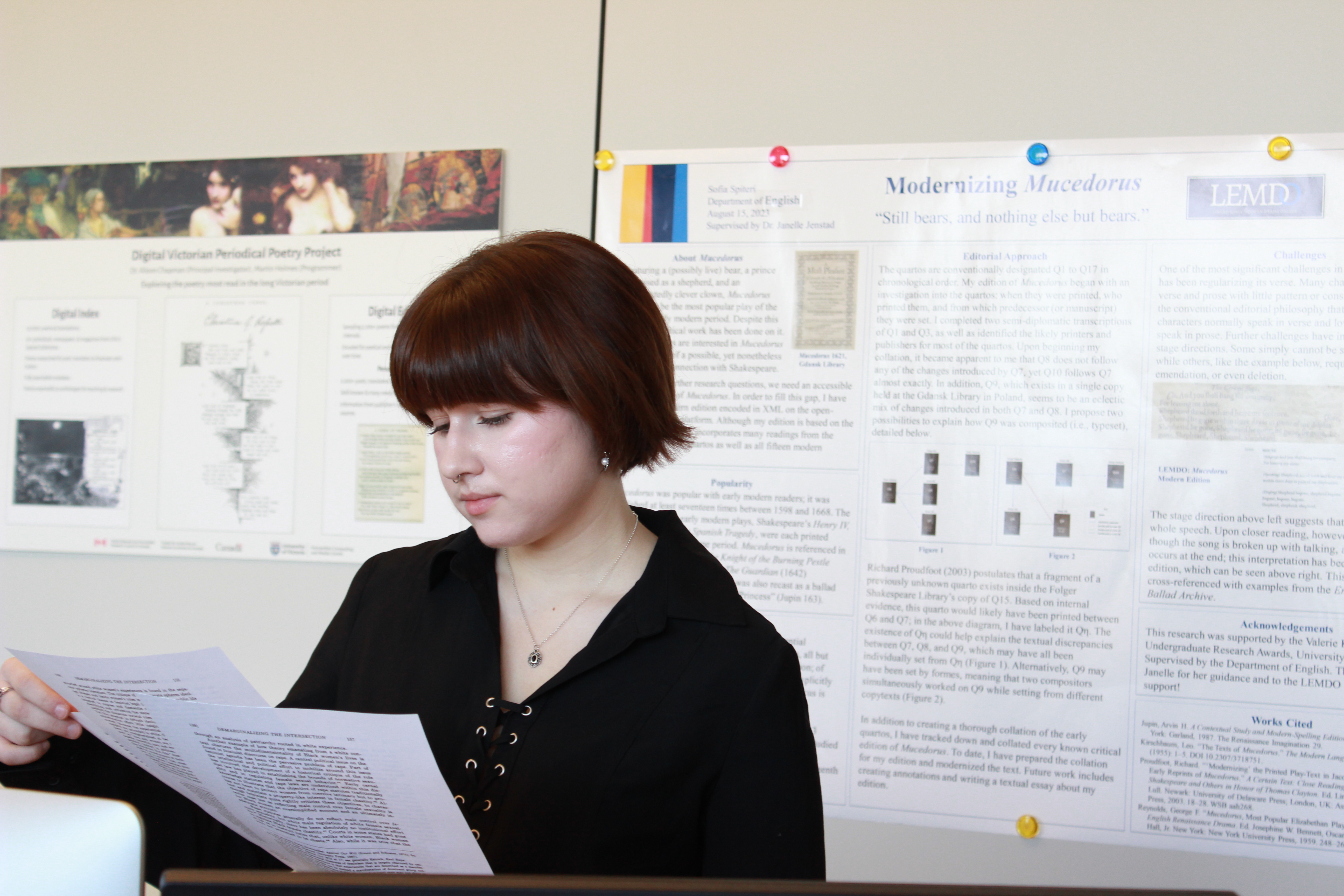 Sofia is reading while standing in front of her research poster.