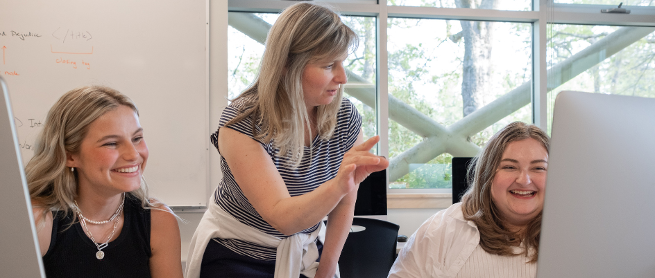 Students and instructor at a desk.