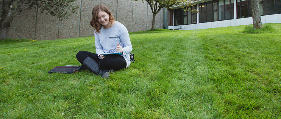 Student sitting on the grass reading