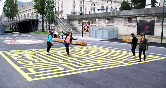 Four students wandering through a maze painted on a Parisian sidewalk 