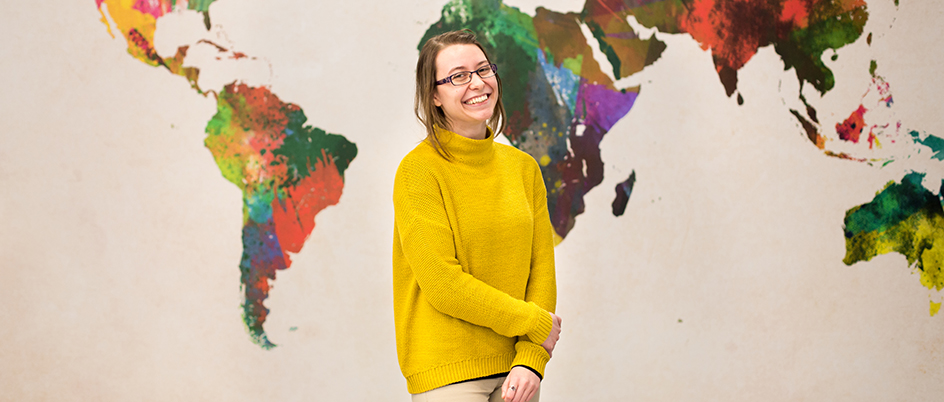 Female student standing in front of a world map