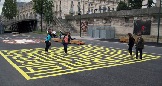 Four students wandering through a maze painted on a Parisian sidewalk 