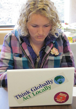 student with laptop and think globally sticker