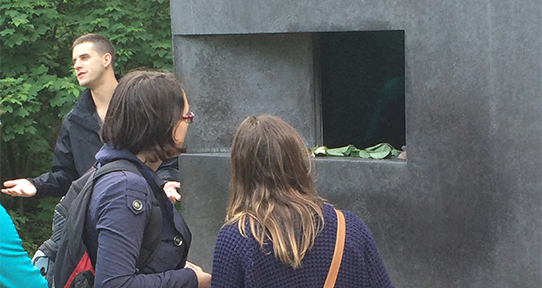 two students looking in the glass of a memorial