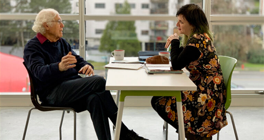 An image of two people in discussion across from each other at a table.