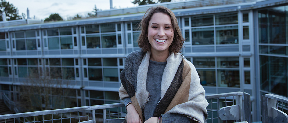 Smiling student on the UVic campus with a building in the background