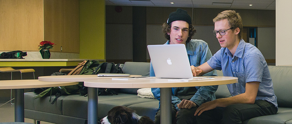 Two students on a laptop in a UVic building