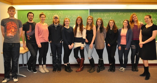 Twelve students looking at the camera in a straight line in a classroom