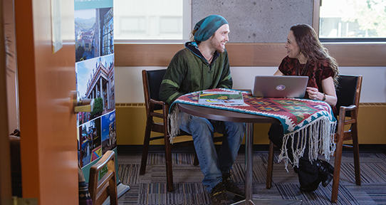 Cedar Luke talking to Beatriz de Alba-Koch at a table in a reading room