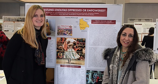 Two women standing in front a poster