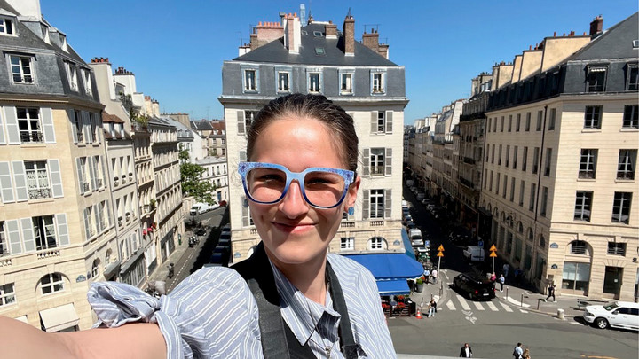 UVic French student in Paris, taking a selfie on a balcony with a view of the city behind.