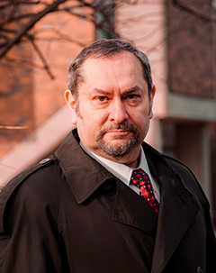 Serhy Yekelchyk, a man with dark hair and a short beard, outside wearing a dark jacket and red patterned tie.