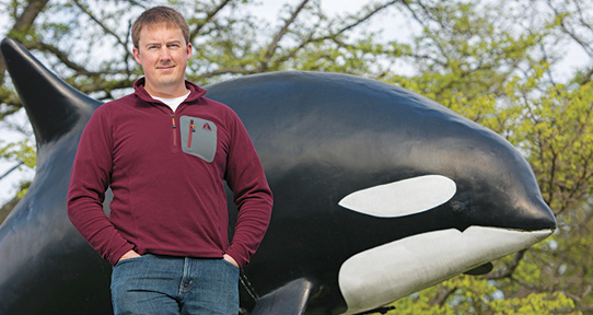 Colby standing in front of an Orca statue