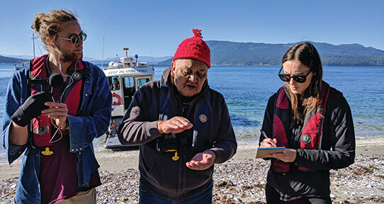 Penelakut Elder Auggie Sylvester sharing Indigenous histories of Portland Island with students Mike Graeme and Tessa Gaudet