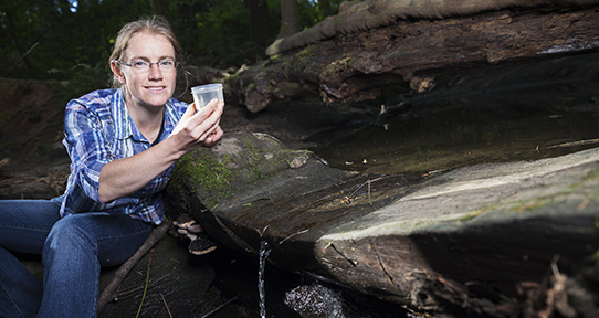 Buckley by a stream holding a cup of water