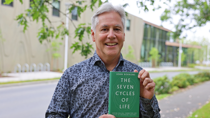 John Borrows holding his book The Seven Cycles of Life.