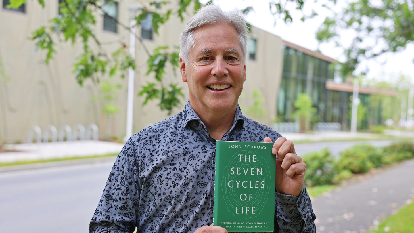 John Borrows holding his book The Seven Cycles of Life.