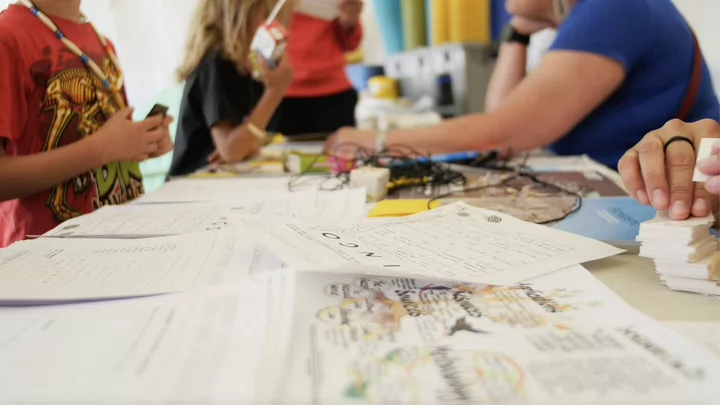 Students sit around a table with papers.