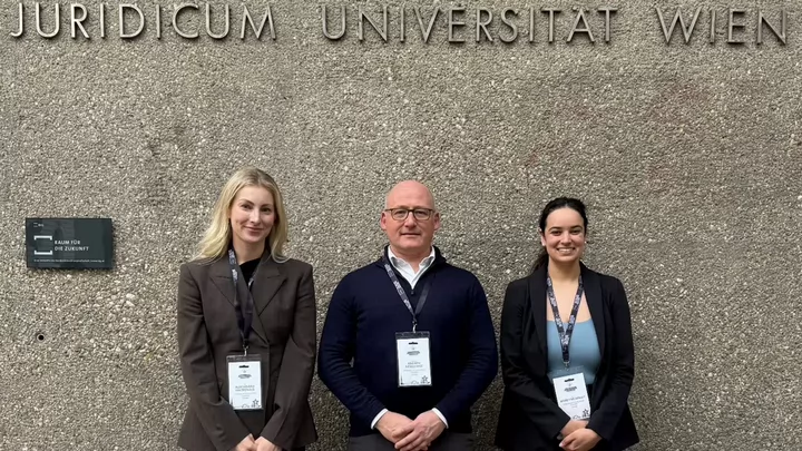 Three people stand together at a moot competition.