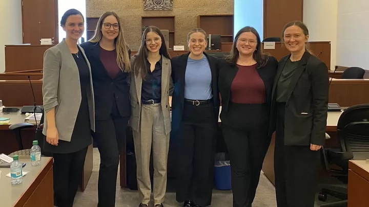 Six people stand together at a moot competition.