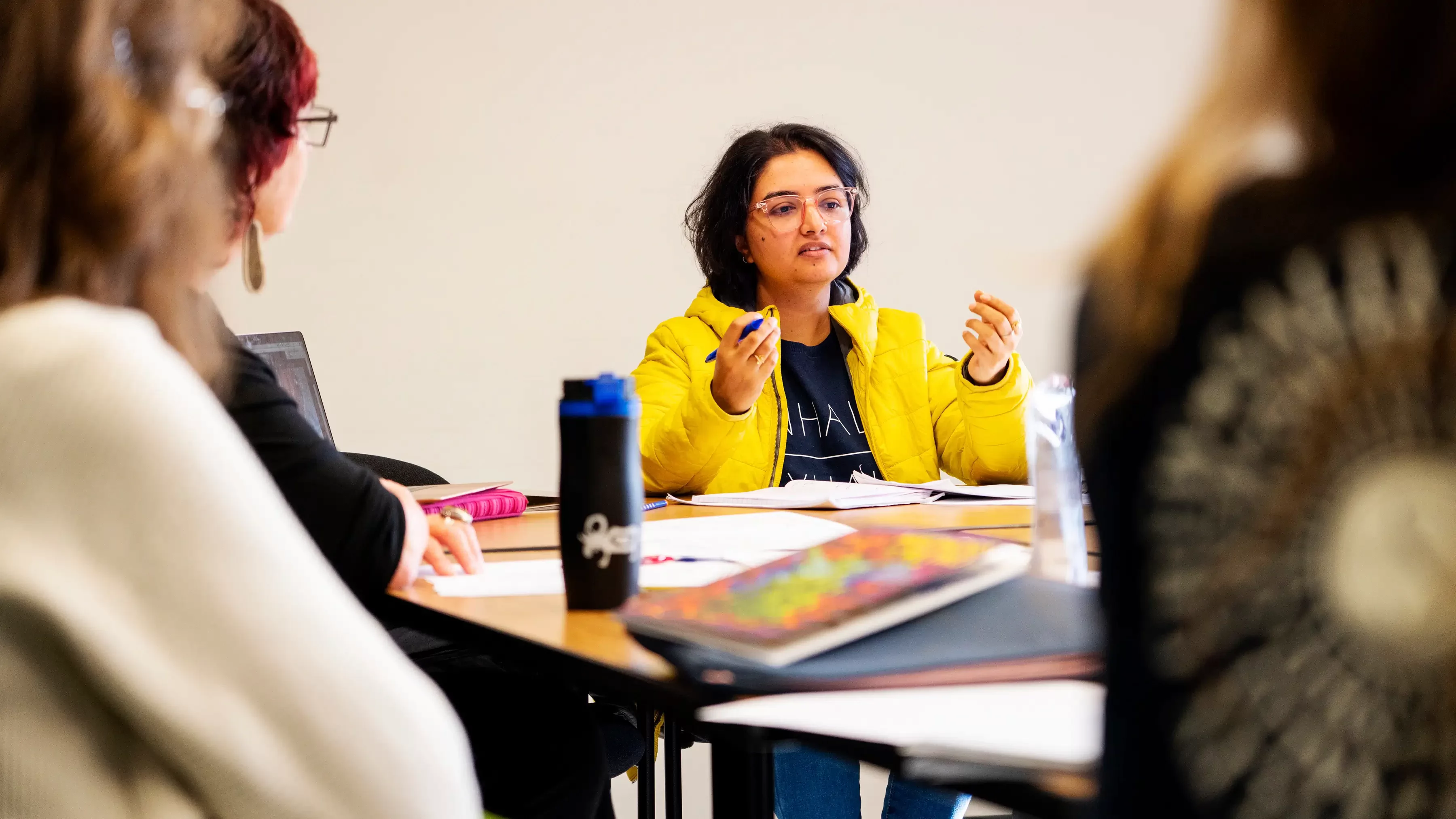 A woman holds her hands up while speaking to a group.