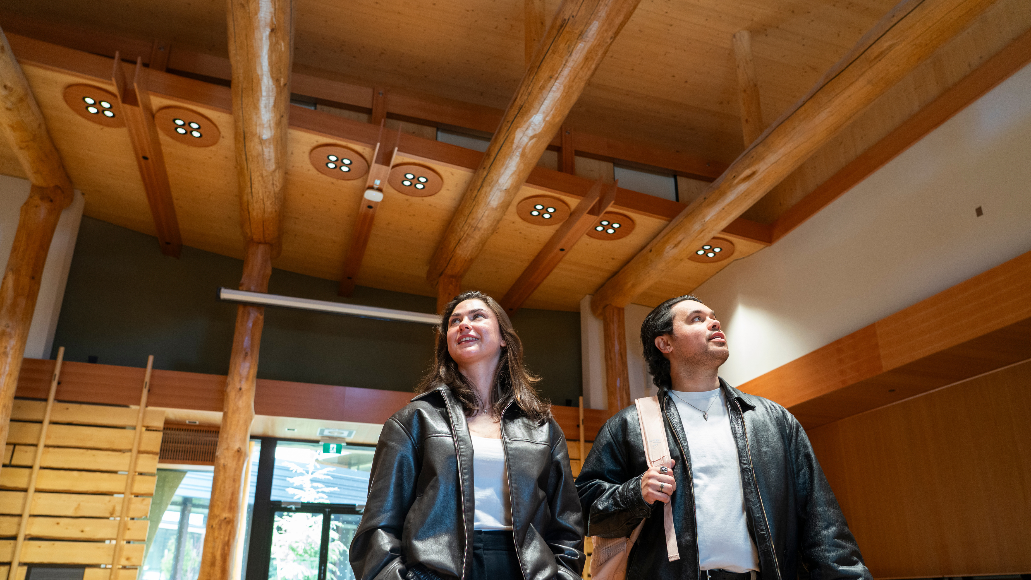 Two students look up at the ceiling of the the Large Gathering Space of the Indigenous Law Wing