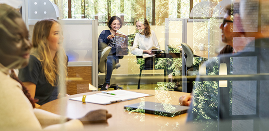 Students sit around several table in the library