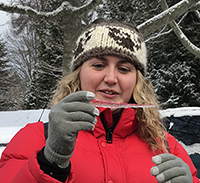Picture of Alexa Powell in a snowy forest holding an icicle.