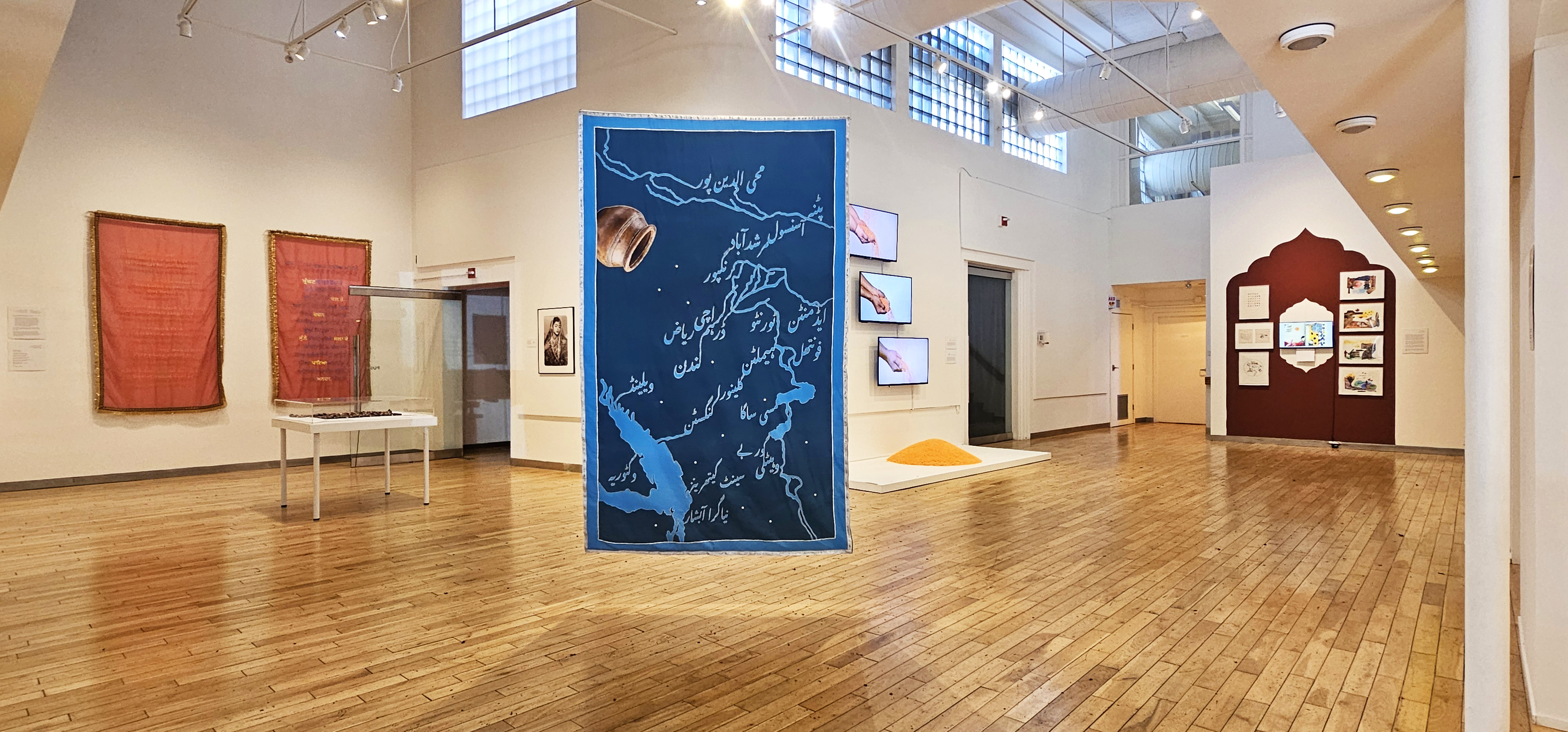 Wide view of the main gallery space for Doug LaFortune's Salish Lines exhibit. Paintings are visible on the walls in the background. 