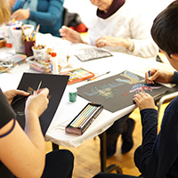 A photo of participants making art around a table. 