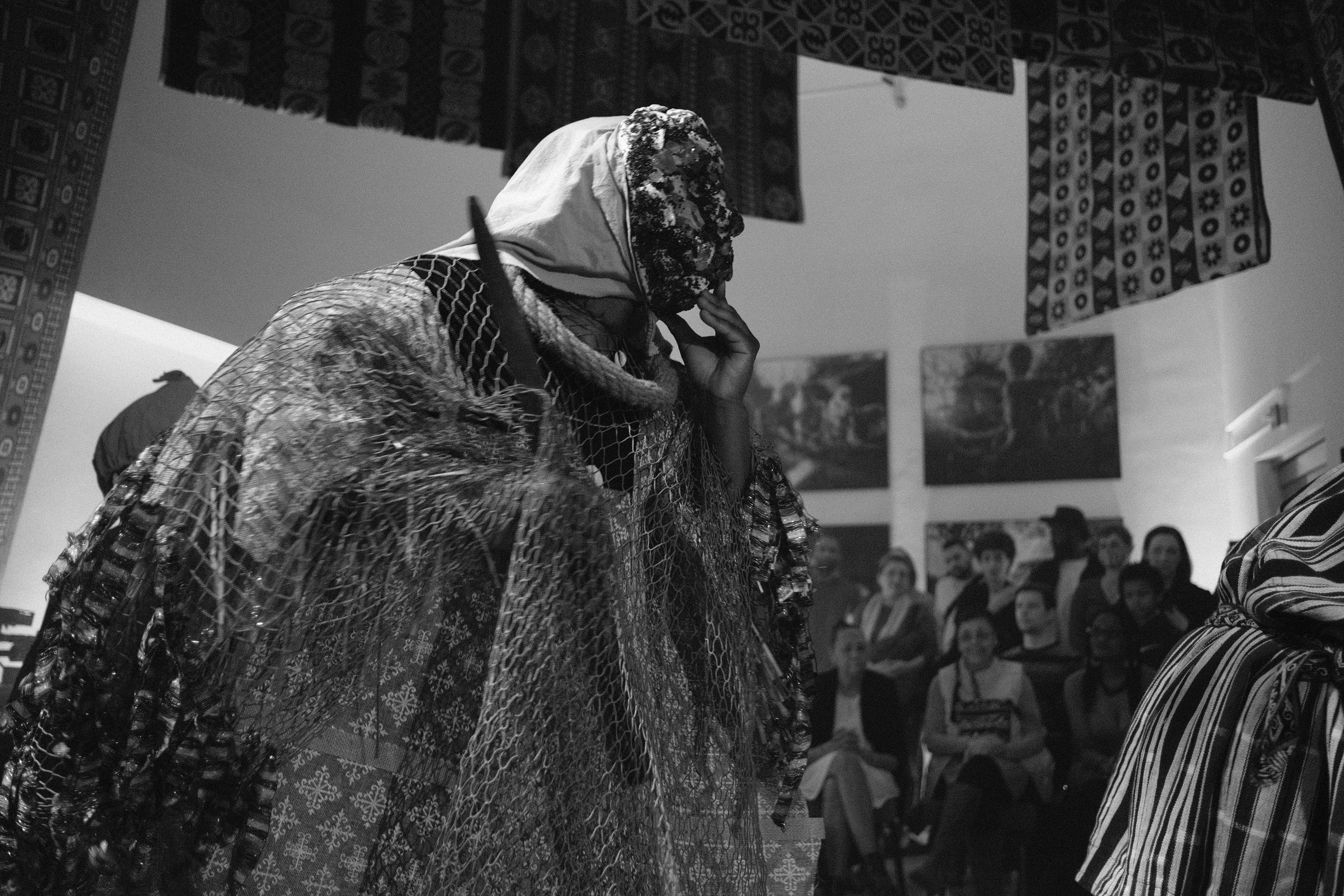 Black and white photo of masked dancer in a robe