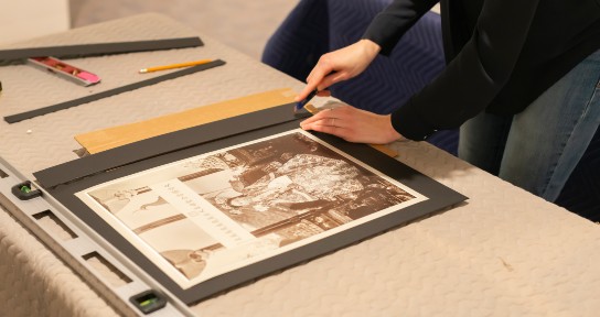 close-up of hands cutting the mat for an artwork to the appropriate size