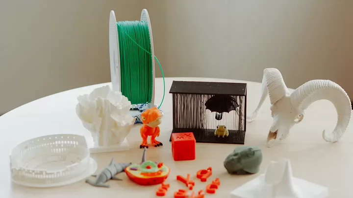 Collection of 3D printed objects, including a mini T-rex, skull, and model colosseum.