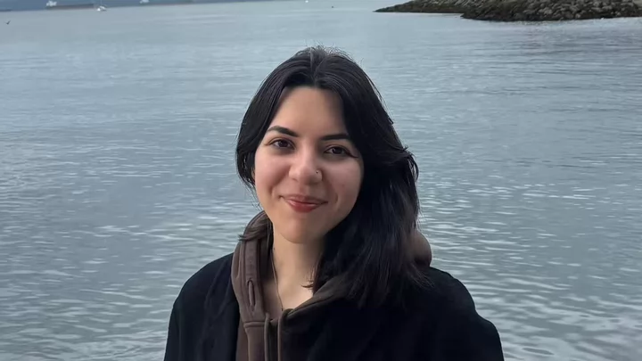 Daniela wearing a hoodie and jacket in front of the ocean