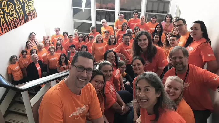 Several library employees wearing orange shirts gather in the staircase