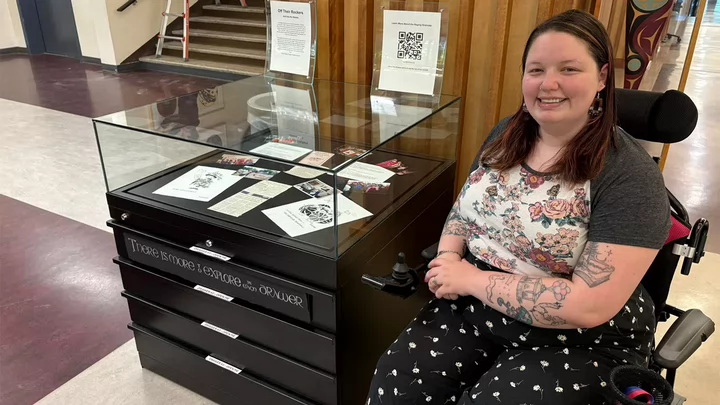 A female student is beside a display case in the library.