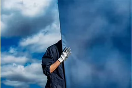 Half a body is shown with a hand holding a large blue screen.